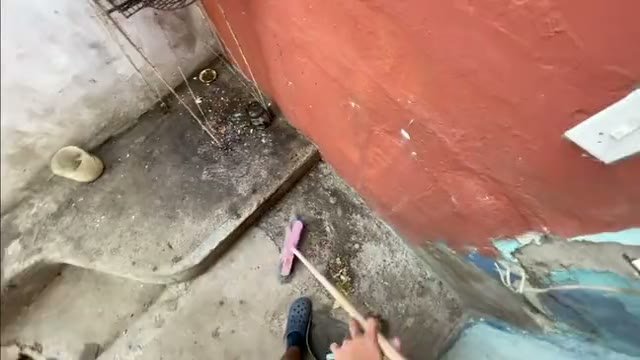 Varrição do quintal com vassoura, gravada em primeira pessoa, com a mão e o cabo no quadro