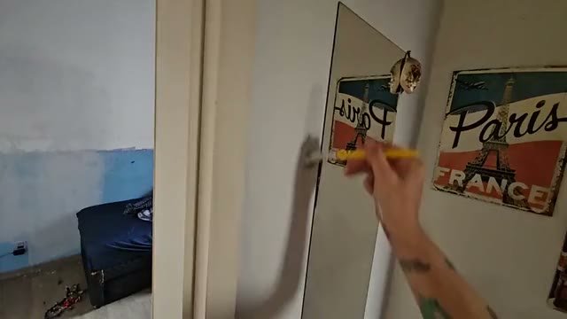 Pincel pintando o batente de uma porta, visto em primeira pessoa